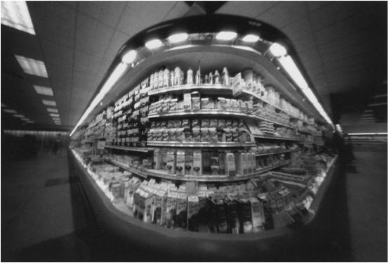 There is a photograph of the dairy section in a supermarket as seen through a fisheye camera lens. 